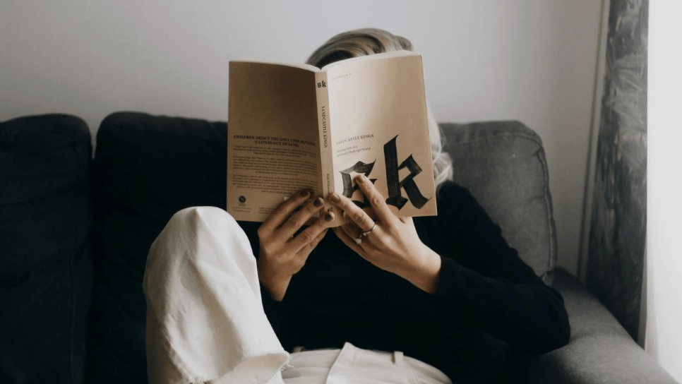 Person reading a book with face obscured